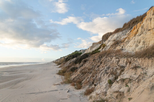 Natural coastal landscape with eroded cliffs, sand dunes and Atlantic shoreline at Cuesta Maneli Beach, Huelva, Spain. Ideal for travel, nature and environment concepts.