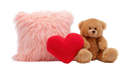 A pink pillow with a heart on it sits next to a teddy bear