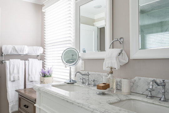 Elegant bathroom vanity with marble countertop, double sink, mirrors, chrome fixtures and white towels