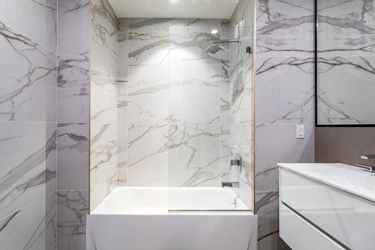 Modern bathroom with marble tile walls and frameless glass shower