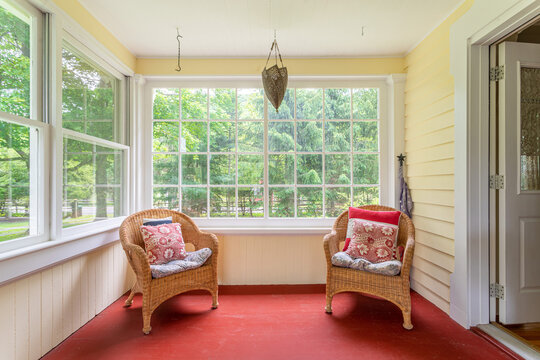 Bright sunroom interior with wicker chairs, large windows, and garden view