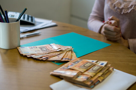 Billetes de cincuenta euros dispuestos en forma de abanico sobre una superficie verde, con m&aacute;s fajos de dinero en primer plano.