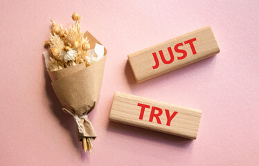 Fototapeta premium Just try symbol. Concept words Just try on wooden blocks. Beautiful pink background with bouquet of flowers. Business and Just Try concept. Copy space.