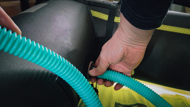 A person attaching a pump hose to inflate an ice kiting wing or wing sail for kite winging on a frozen lake in winter.