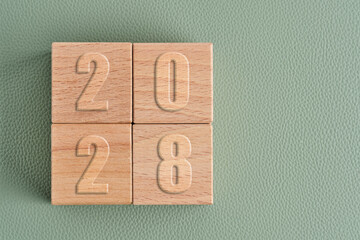 Wooden blocks showing year 2028 on green leather background. Concept for future and calendar.