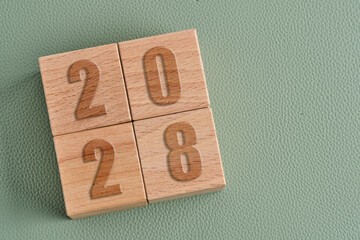 Wooden blocks showing year 2028 on green leather background. Concept for future and calendar.