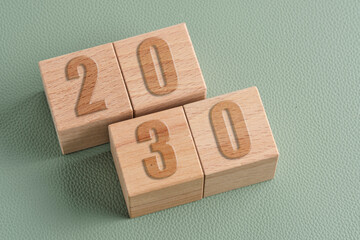 Wooden cubes with numbers 2030 on green background. Concept of future planning and long term goals.