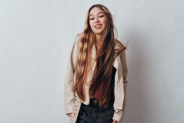 Fototapeta premium Young woman with long hair wearing casual outfit and light jacket standing against white background with eyes closed and relaxed expression. Female, fashion, portrait, model.
