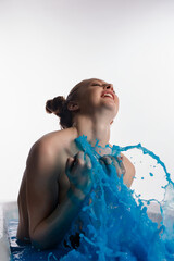 Elegant woman expressing joy while playing with blue water in a serene setting