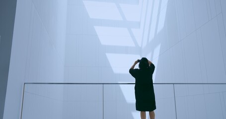 Adult person photographing a striking abstract interior with a smartphone in a futuristic, minimalist building, representing contemporary design, digital capture, and urban exploration. © HarryKiiM Stock