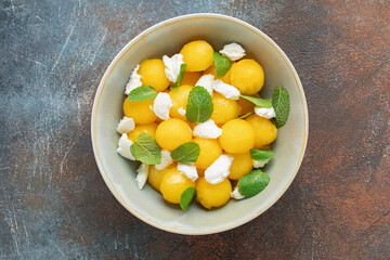 Summer fresh salad with yellow watermelon, ricotta, and mint leaves in  bowl on the table. Top view © murziknata