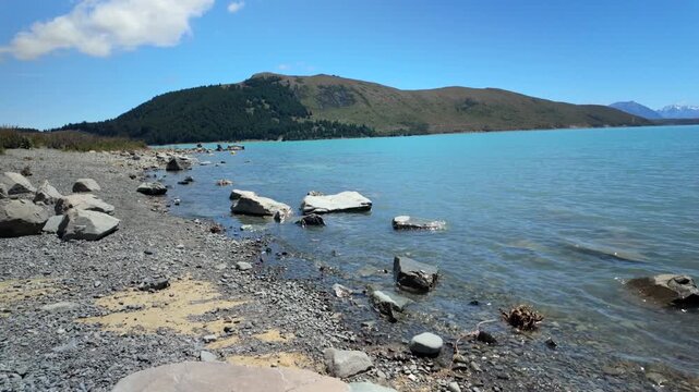 Rocky Lakeshore With Clear Blue Water And Distant Hills