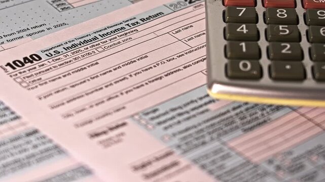 Accountant using a calculator to complete a 1040 tax form before the filing deadline