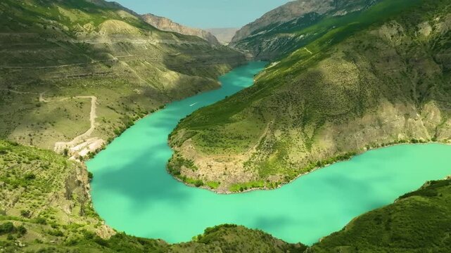 Drone footage captures the stunning natural beauty of the Sulak Canyon in the Republic of Dagestan, North Caucasus Mountains, Russia. The bright, emerald-blue water of the winding Sulak River flows th