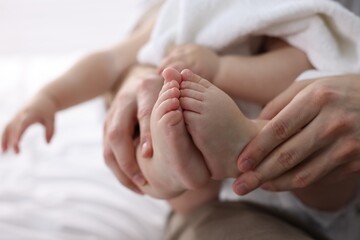 Father holding his cute little baby wrapped with towel on bed at home, closeup