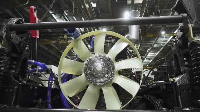 New powerful engine with cooling fan, mounted on chassis in assembly workshop at machinery plant. Intermediate stage of truck assembly at factory.