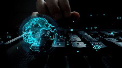 A hand interacts with a keyboard while a glowing hologram of the globe appears, symbolizing digital connection and the integration of technology in our lives. Xenic