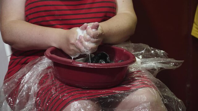 Caucasian woman hand washing socks in basin of soapy water closeup. Washing by hand due to power outage and poverty. Manual labor in home.
