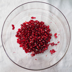 Fresh pomegranate seeds in glass bowl on white background