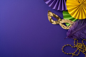 Obraz premium Vibrant Mardi Gras scene featuring a gold sequin mask, purple feather, and colorful paper decorations for a festive celebration. Beads trail across a rich purple backdrop, evoking carnival style
