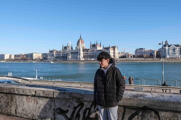 Fototapeta premium Young man enjoying budapest danube river cityscape and parliament building