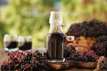 Black elderberry syrup on a table outdoors