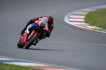 High angle view of a professional rider on a red sport motorcycle leaning into a corner at high speed on a race track circuit © Jakub Sisulak