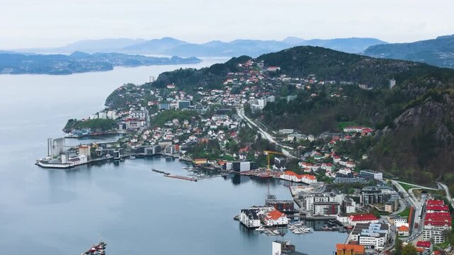 orange white roofed homes nestled along edge vast calm fjord evergreen covered mountain bright green rectangular sports field norway bergen city center port white-roofed evergreen-covered 