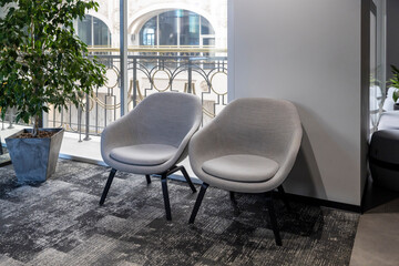 Naklejka premium Contemporary office or business lounge balcony terrace featuring two gray upholstered modern accent chairs with black metal legs, 