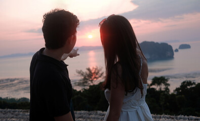 Fototapeta premium Romantic Couple Watching Sunset Over Tropical Sea and Islands at khaothong , Krabi