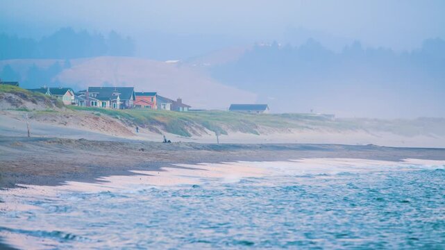 Scenic view of the historic Heceta Head Lighthouse and coastline in Oregon, USA, during the evening. The footage captures the dramatic coastal landscape, waves crashing on the shore, and the iconic wh