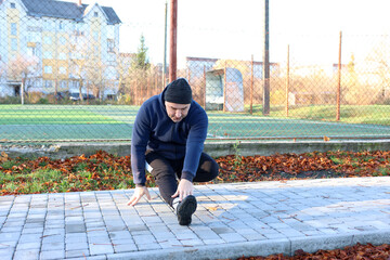 Man performing side bend with hand on waist during warm-up on an outdoor sports ground