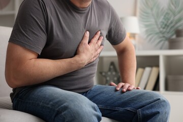 Heart attack. Man suffering from pain in chest indoors, closeup