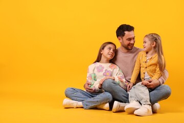 Portrait of father and his daughters on orange background, space for text