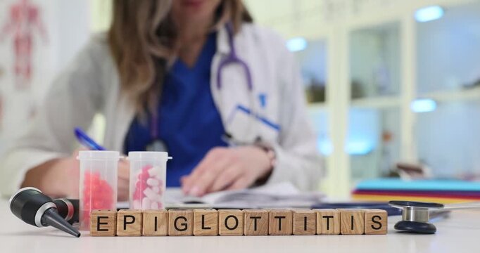 Wooden cubes form word Epiglottitis indicating diagnosis assigned to patient. Female physician writes treatment plan focused on infection control