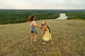 Mom and daughters having fun on the meadow to have a picnic to enjoy the summer day