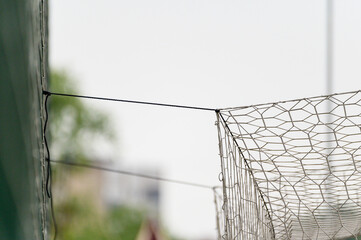 a soccer goal net tied to a green fence
