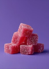 Pile of red sugar-coated fruit jellies stacked against a vibrant purple background