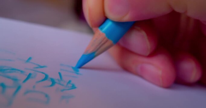 Close-up shot of hand drawing abstract pattern on paper with blue pencil.