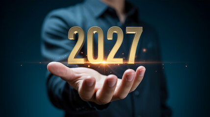Man holding 2027 in golden numbers with glowing effect in dark blue background for new year