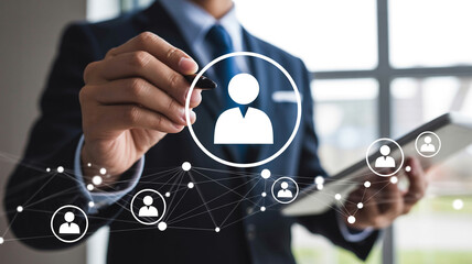 Businessman interacting with virtual network interface with person icons in modern blue glow on digital tablet for corporate communication