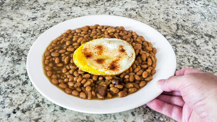 Dish of beans with fried egg served on a plate at home kitchen during meal time