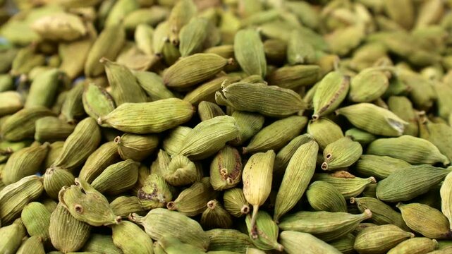 Dried green cardamom pods condiment falling down close up