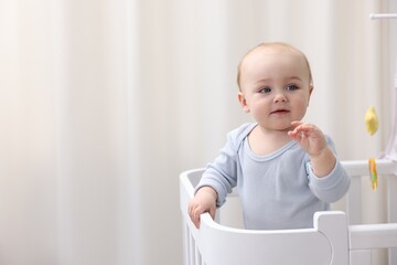 Cute little baby in crib at home. Space for text