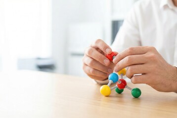 Person builds a model using colorful pieces on a wooden table in a bright room during the day
