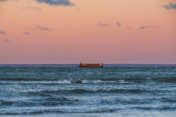 Obraz premium Historic Soviet submarine refueling pier in the Baltic Sea near Viimsi peninsula with sunset sky and choppy sea waves.