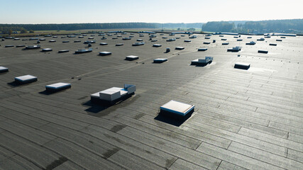 Large industrial flat roof with skylights on modern warehouse building in rural landscape © moonphasestudio