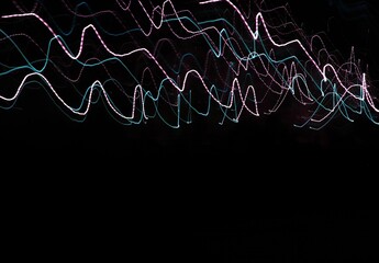 Linear composition. Аbstract long-exposure photograph depicting colorful neon light trails against a dark background.