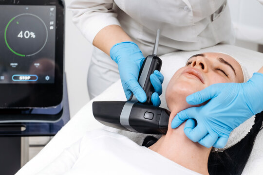 Female patient receiving microneedle RF lifting on the neck in a beauty clinic with professional equipment and digital control. Aesthetic skin tightening procedure. Concept microneedle RF