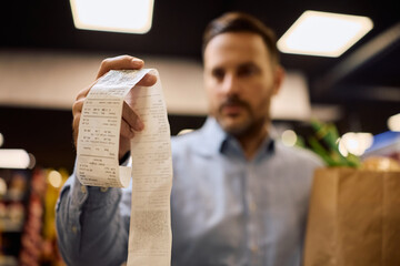 Close up of man checking his bill in supermarket.